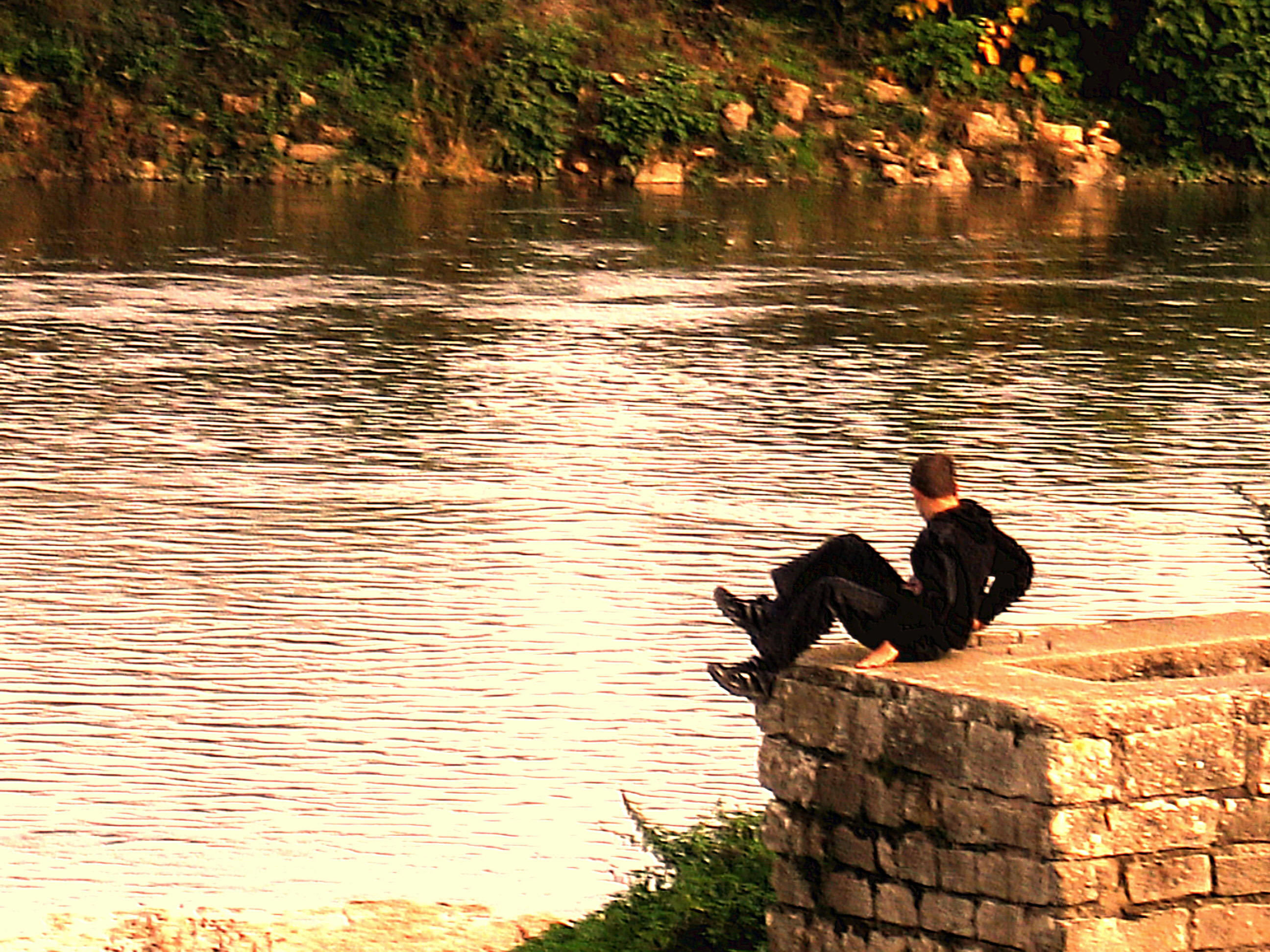bord de Loire, France, on voit un homme assis sur un mur de pierre devant la Loire